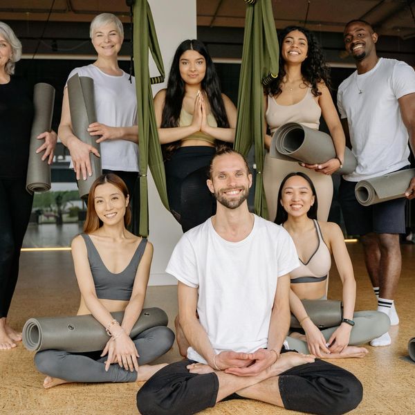 Diverse group of people smiling during a calm yoga session in a bright studio.